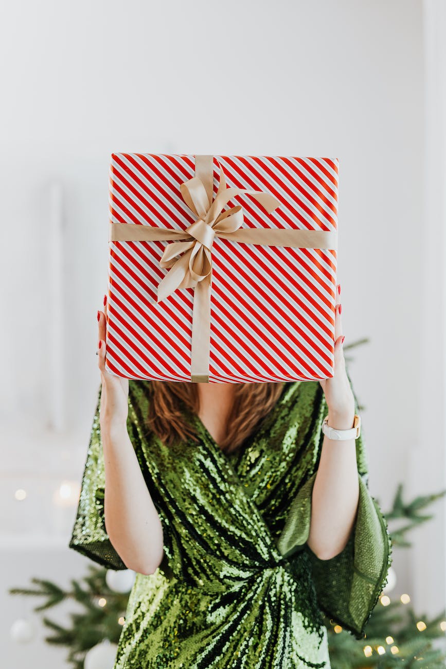 woman in green glittery dress holding a gift box