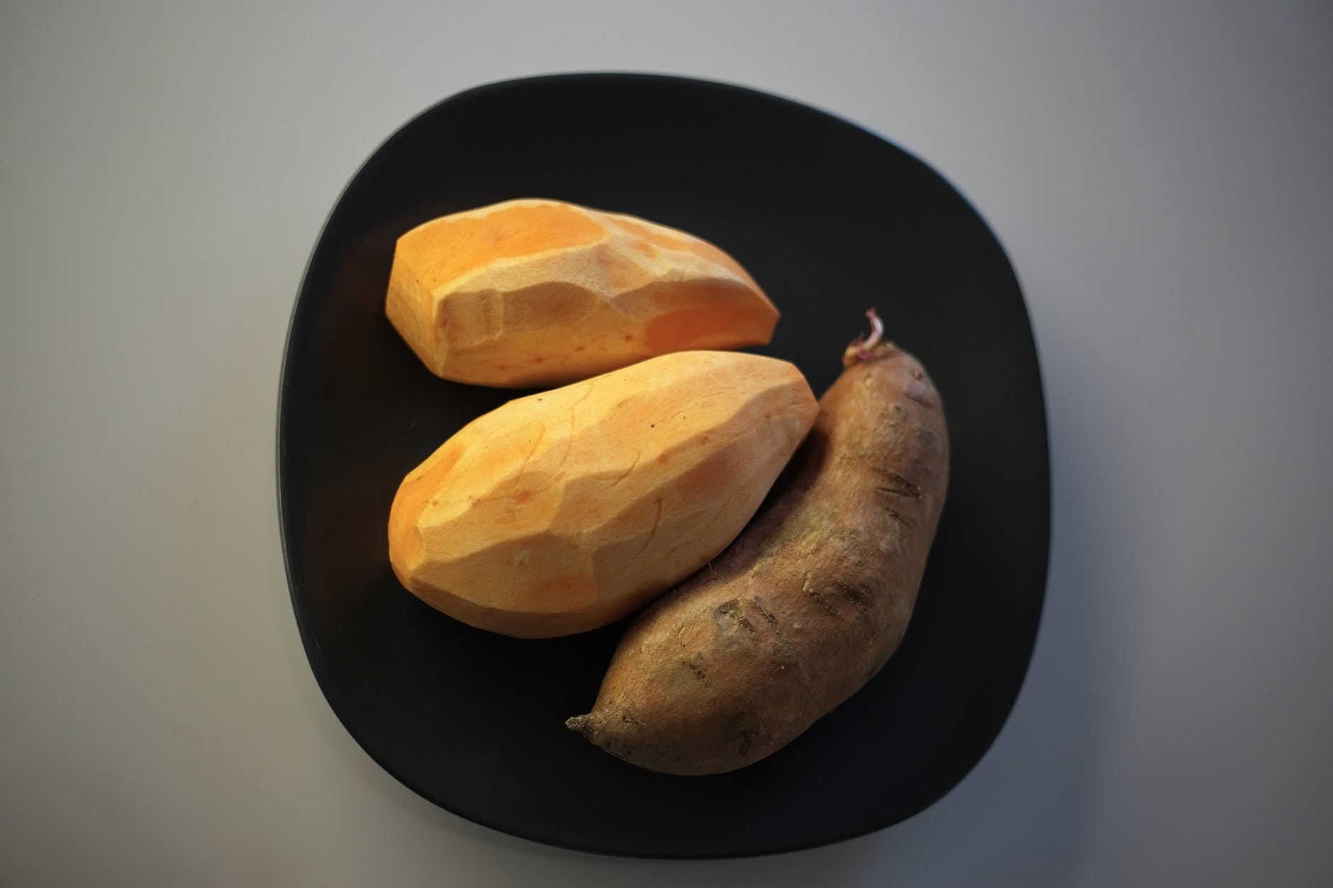 raw batata potatoes on black plate