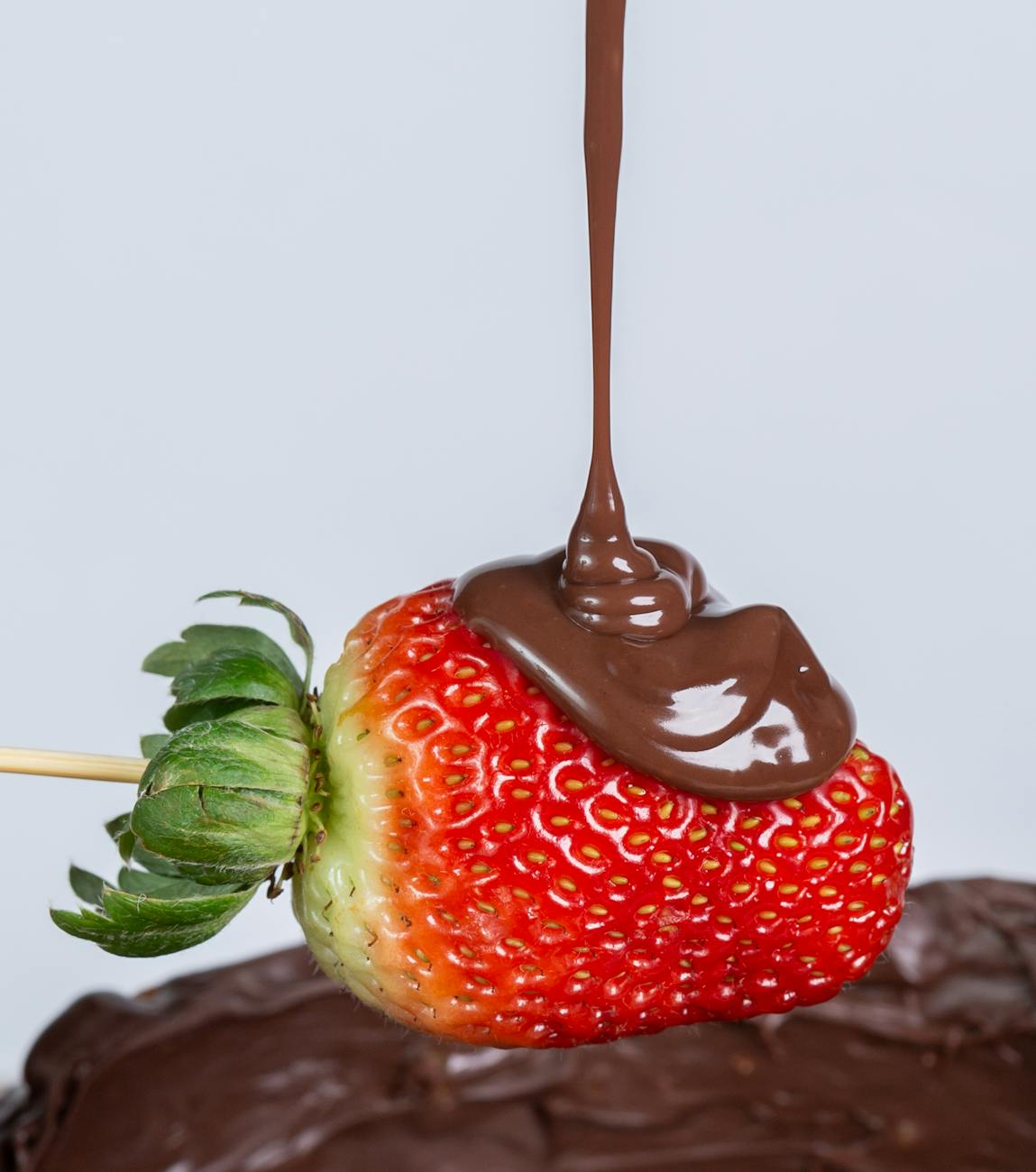 close up of chocolate being poured on a strawberry